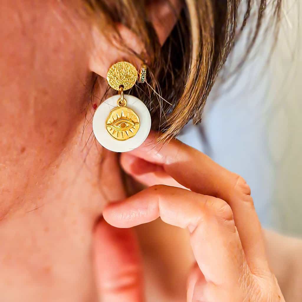 Boucles oeil nacre portées à l’oreille, pour montrer leur longueur élégante et leur aspect lumineux sur une tenue estivale.