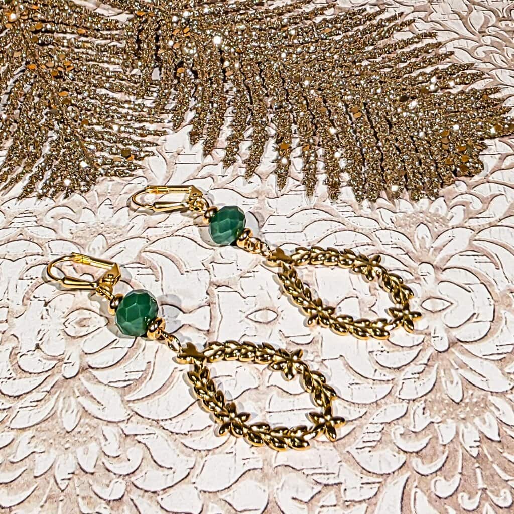 Boucles d’oreilles à couronne de laurier suspendues, montrant leur légèreté et leur éclat doré, idéales pour un look bohème raffiné et naturel