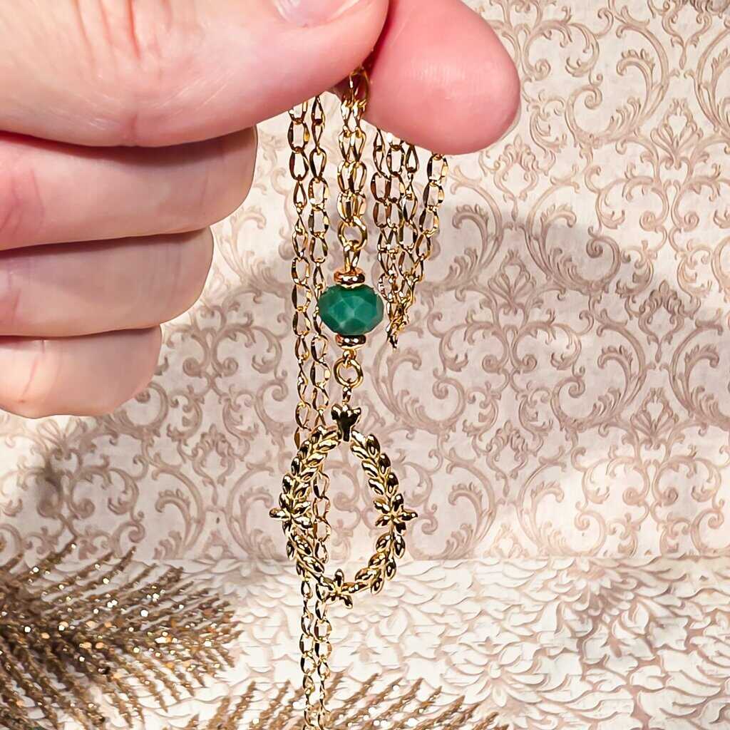 Gros plan sur le pendentif couronne laurier finement travaillé captant la lumière avec éclat sur une chaîne élégante