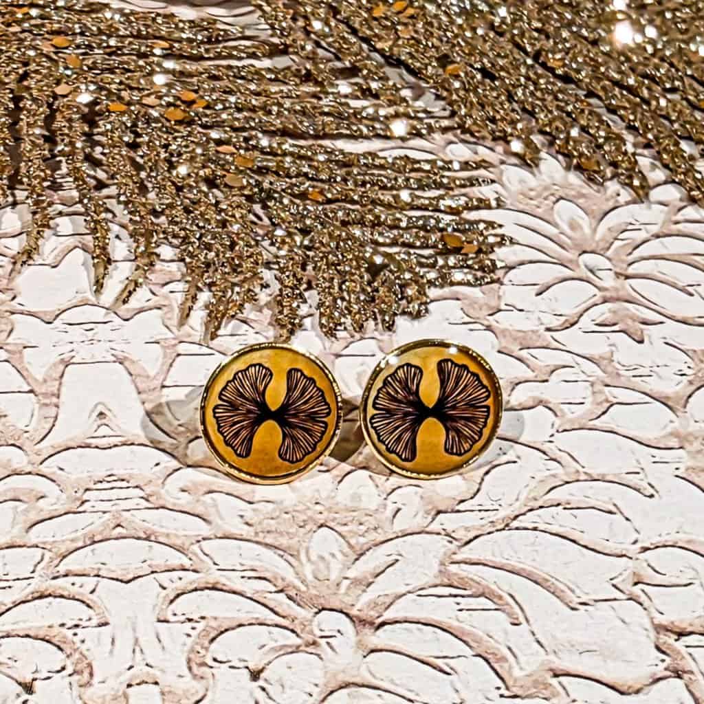Puces d’oreilles motif feuille de ginkgo dorée sur fond clair, légères et brillantes