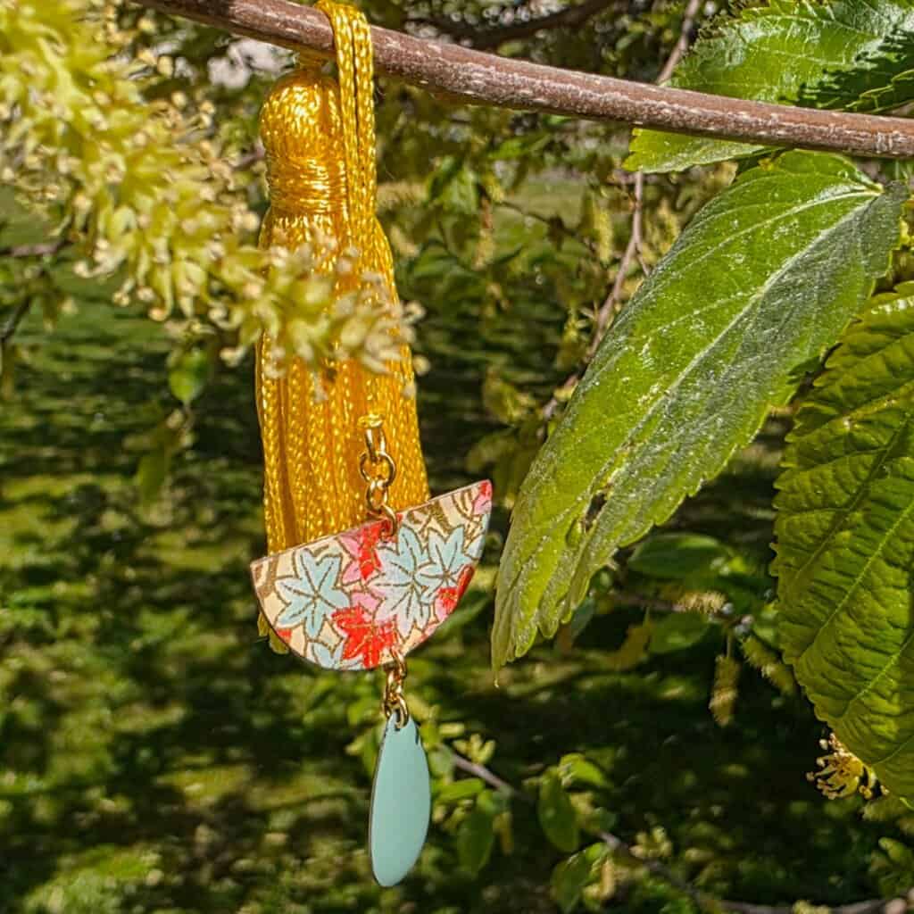 Détail du marque-pages printemps – Pendentif demi-lune en papier japonais verni et résine, motifs feuilles tendres et tons pastels